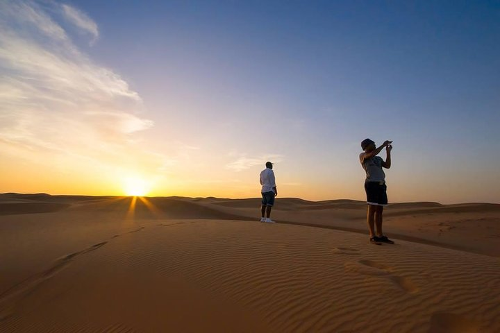 Experience the serene beauty of the desert as the sun sets creating a stunning backdrop for an unforgettable camel trekking adventure and a delicious buffet dinner under the stars.